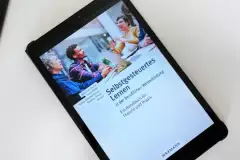 Tablet auf dem das Buchcover der Publikation zu sehen ist