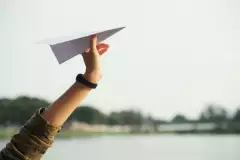 Hand hält Papierflieger
