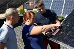 Drei Personen an einer Photovoltaik-Anlage