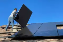Person montiert Solar-Paneele auf einem Dach
