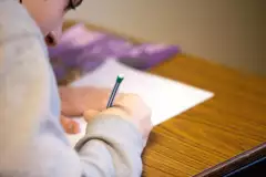Person schreibt mit Stift auf Papier