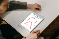 Person schaut auf Tablet, darauf ist das Cover von „weiter bilden“ mit dem Text: Fachkräfte sichern, validieren, anerkennen.
