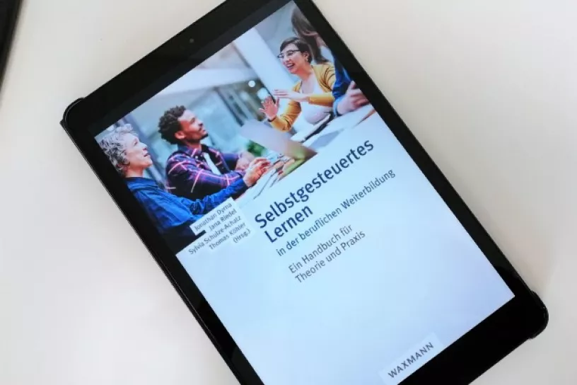 Tablet auf dem das Buchcover der Publikation zu sehen ist