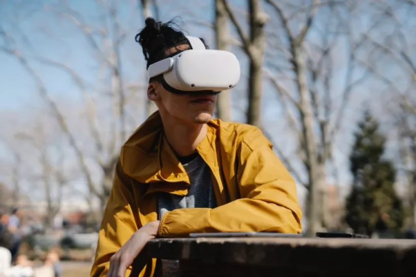 Person sitzt im Freien auf einer Bank und trägt eine VR-Brille