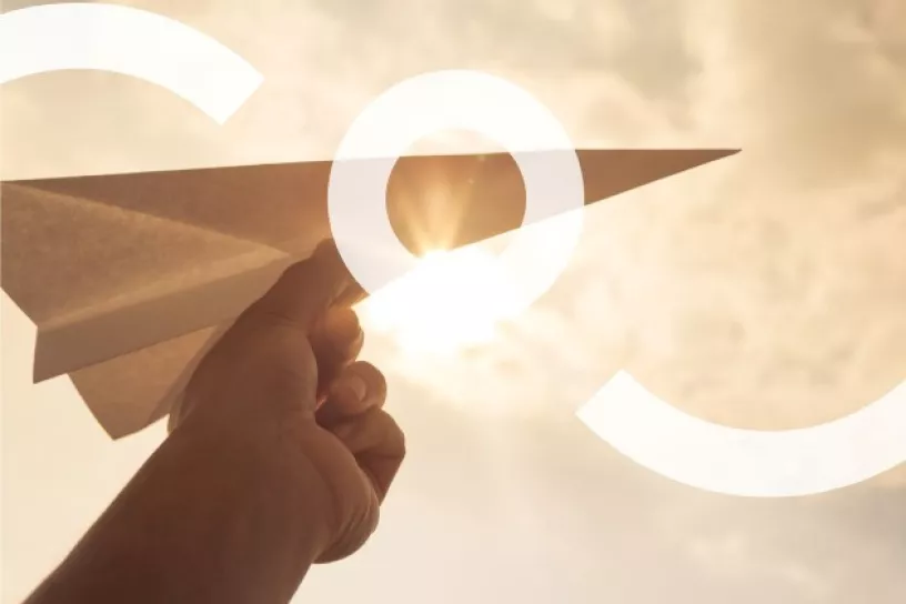 Hand hält Papierflieger, darüber ein Logo