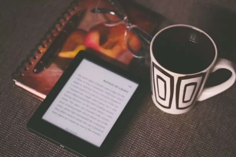 Tablet, daneben Kaffee, Brille und Notizbuch