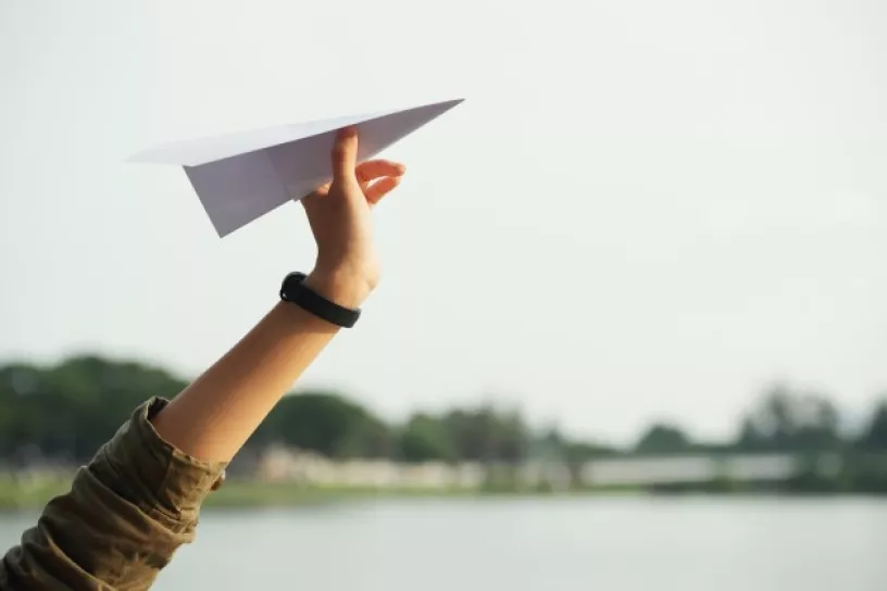 Hand hält Papierflieger