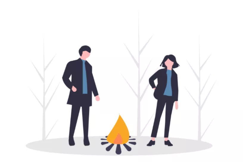 Zwei Personen stehen neben einem Lagerfeuer.