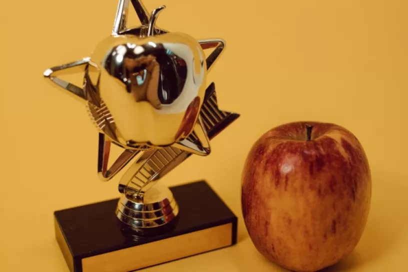 Pokal, daneben ein Apfel