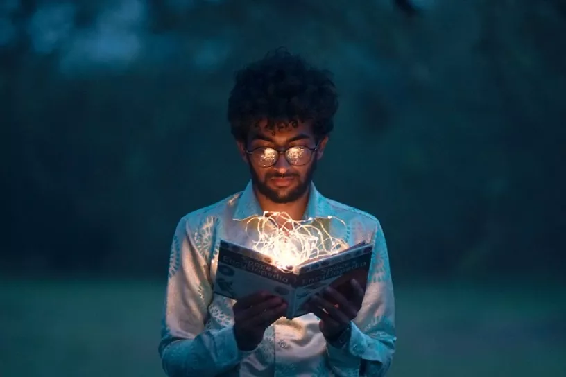 Mann hält Buch mit Lichterkette