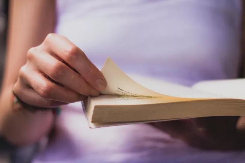 Person blättert eine Seite im Buch um.