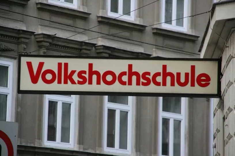 Schild mit der Aufschrift "Volkshochschule" vir einem Haus