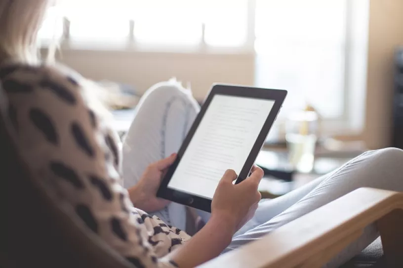 Ausschnitt einer Person, die etwas auf einem Tablet liest