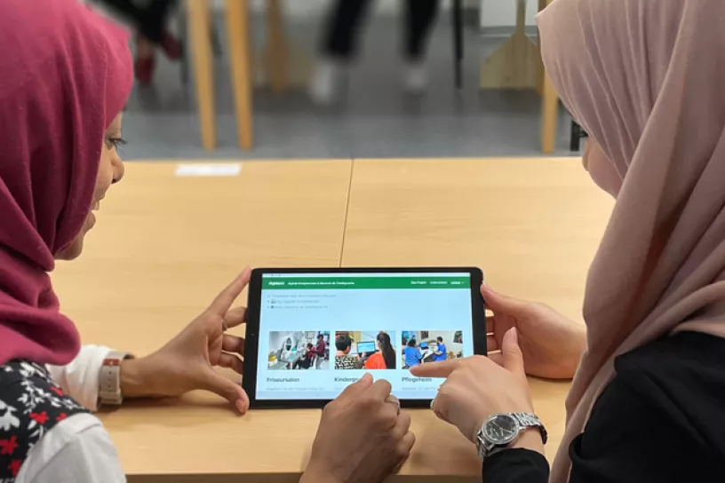 Zwei Teilnehmerinnen arbeiten an einem Tablet.