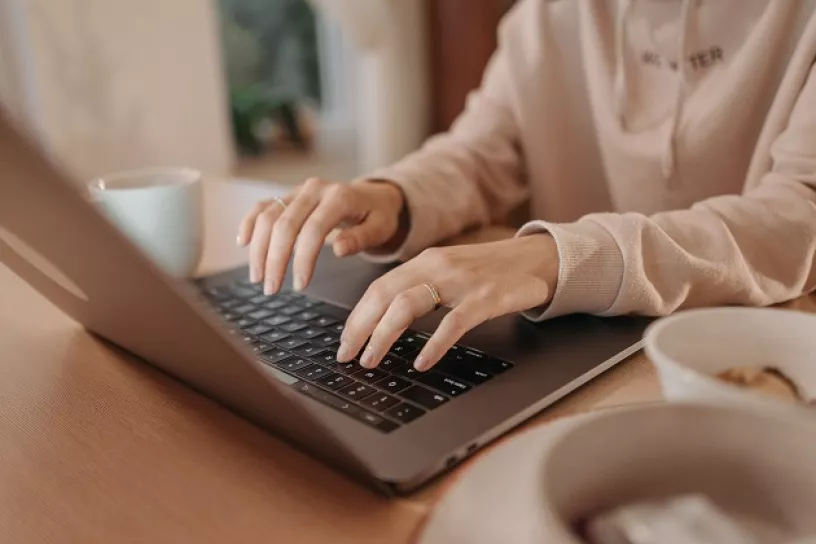 Nahaufnahme einer Person die an einem Laptop arbeitet