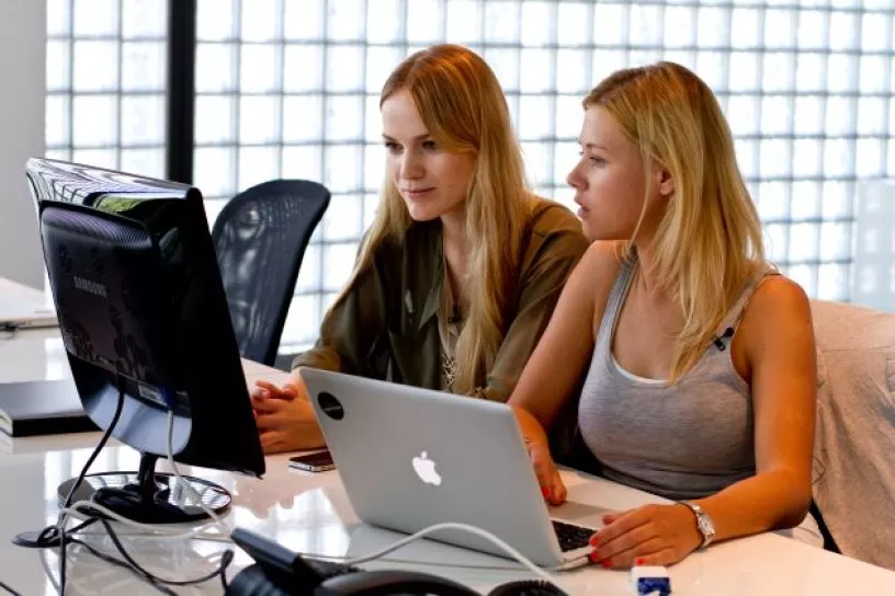 zwei Personen sitzen vor zwei Computer-Bildschirmen