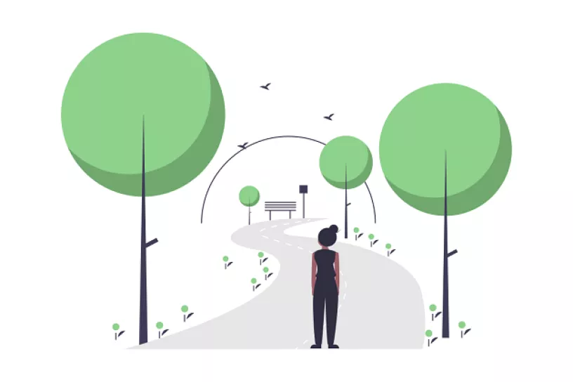 Weg durch einen Park, in der Mitte des Weges steht eine Person, links und rechts befinden sich Bäume