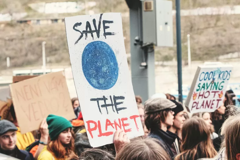 Menschen auf einer Demonstration. Am Schild steht: Save the Planet