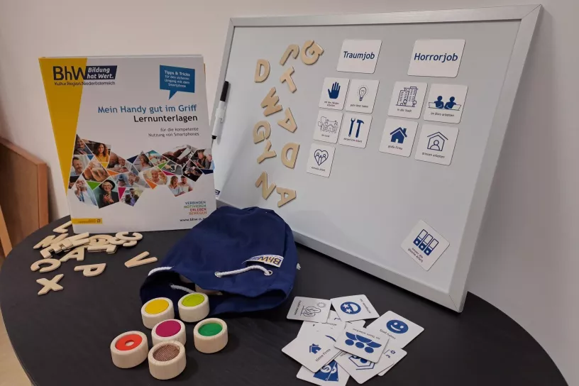 Das Bild zeigt einige der pädagogischen Materialien der BhW Roadshow, unter anderem Magnet-Buchstaben und eine Mappe mit Smartphone-Lernunterlagen