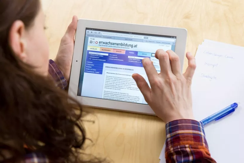 Frau liest mit Touchpad auf www.erwachsenenbildung.at