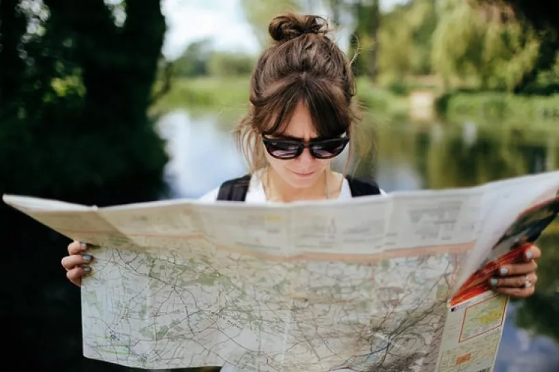 Frau mit Sonnenbrille studiert eine Landkarte